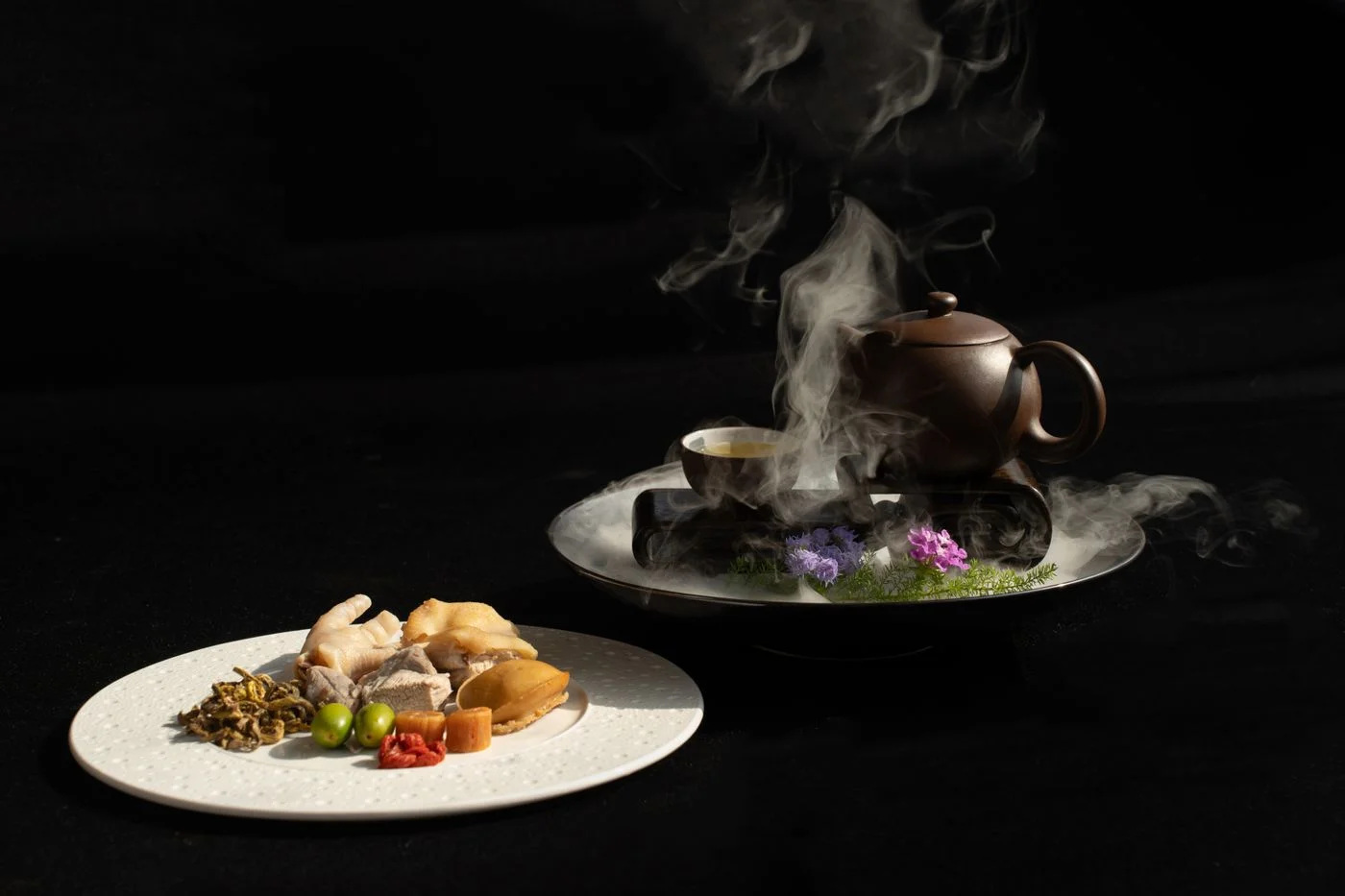 冒著熱氣的茶壺搭配亞洲菜餚，呼應茶與中式餐點搭配傳統 | Steaming teapot paired with Asian dishes, echoing the tradition of tea paired with Chinese cuisine