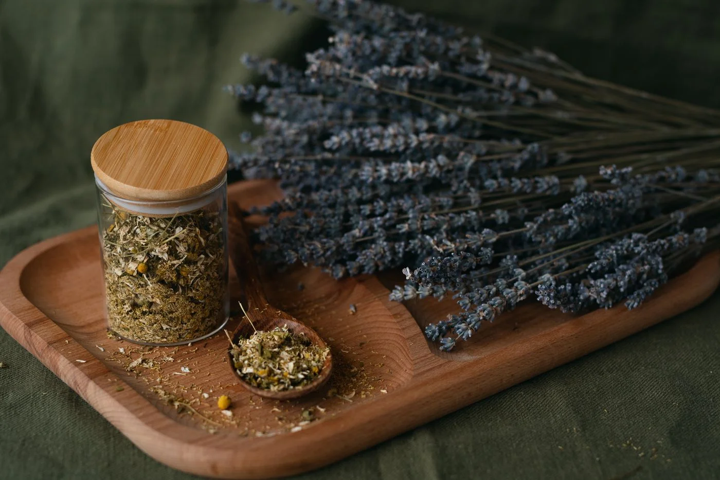 木板上陳列的乾燥薰衣草與香草罐，呈現花草茶的天然原料 | Dried lavender and herb jars arranged on a wooden board, showcasing herbal tea natural ingredients