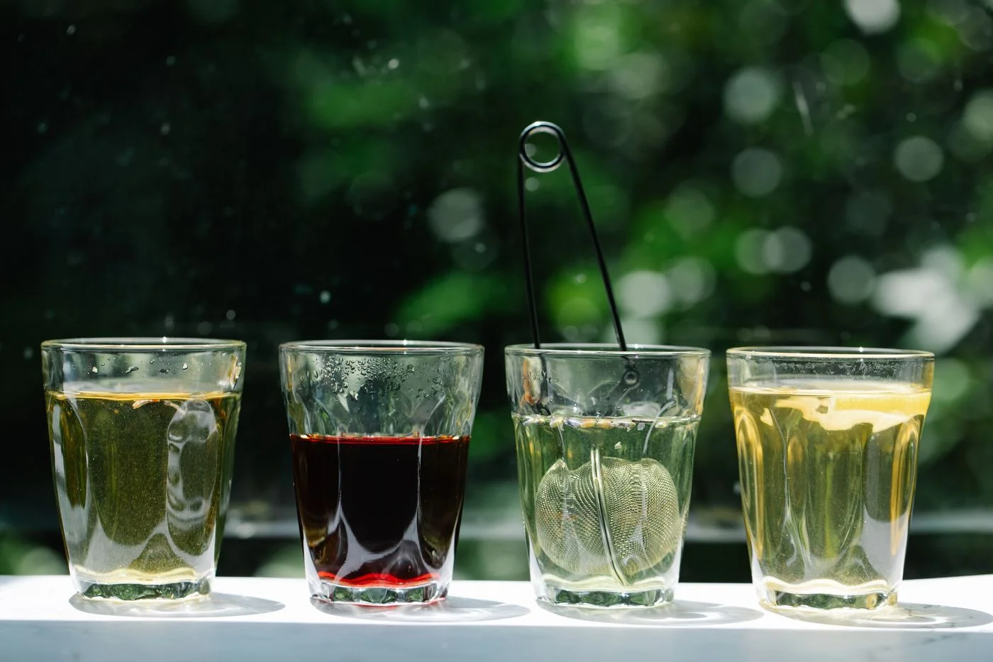 四杯草本茶配茶濾器,呼應寒熱體質選茶 | Four herbal tea cups with strainers, reflecting cold-heat constitution tea selection