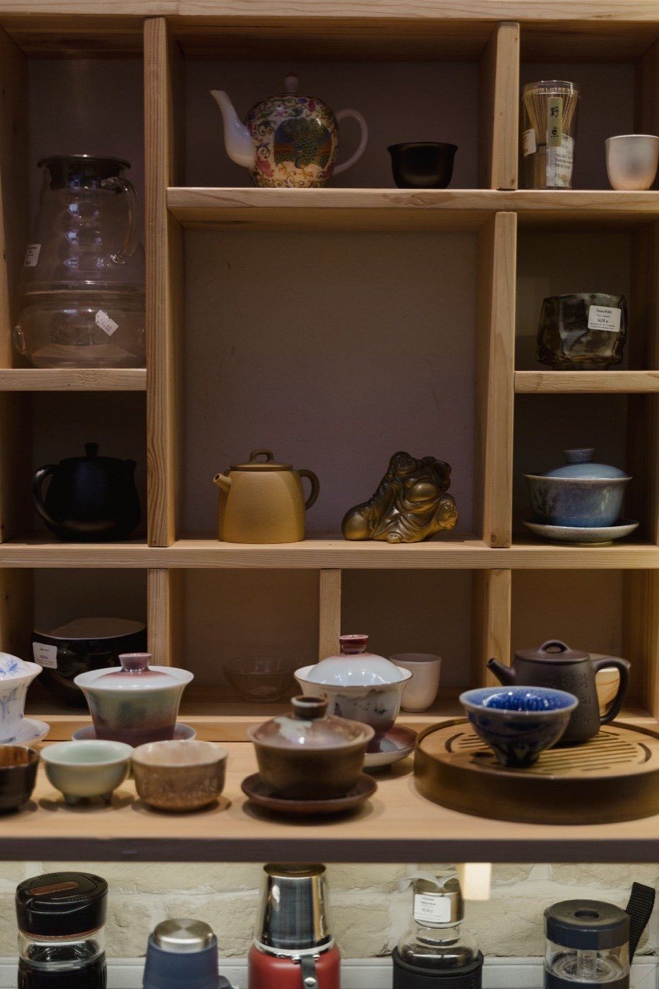 傳統茶具與器具整齊陳列於木製展示架上，呈現實體茶行選購氛圍 | Traditional tea sets and utensils neatly displayed on wooden shelves showcasing physical tea shop atmosphere