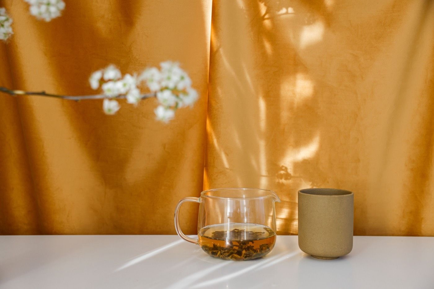 琥珀色茶湯盛於玻璃杯中，暖調光影呈現茶色層次 | Amber tea liquor in glass cup with warm lighting showcasing tea color depth